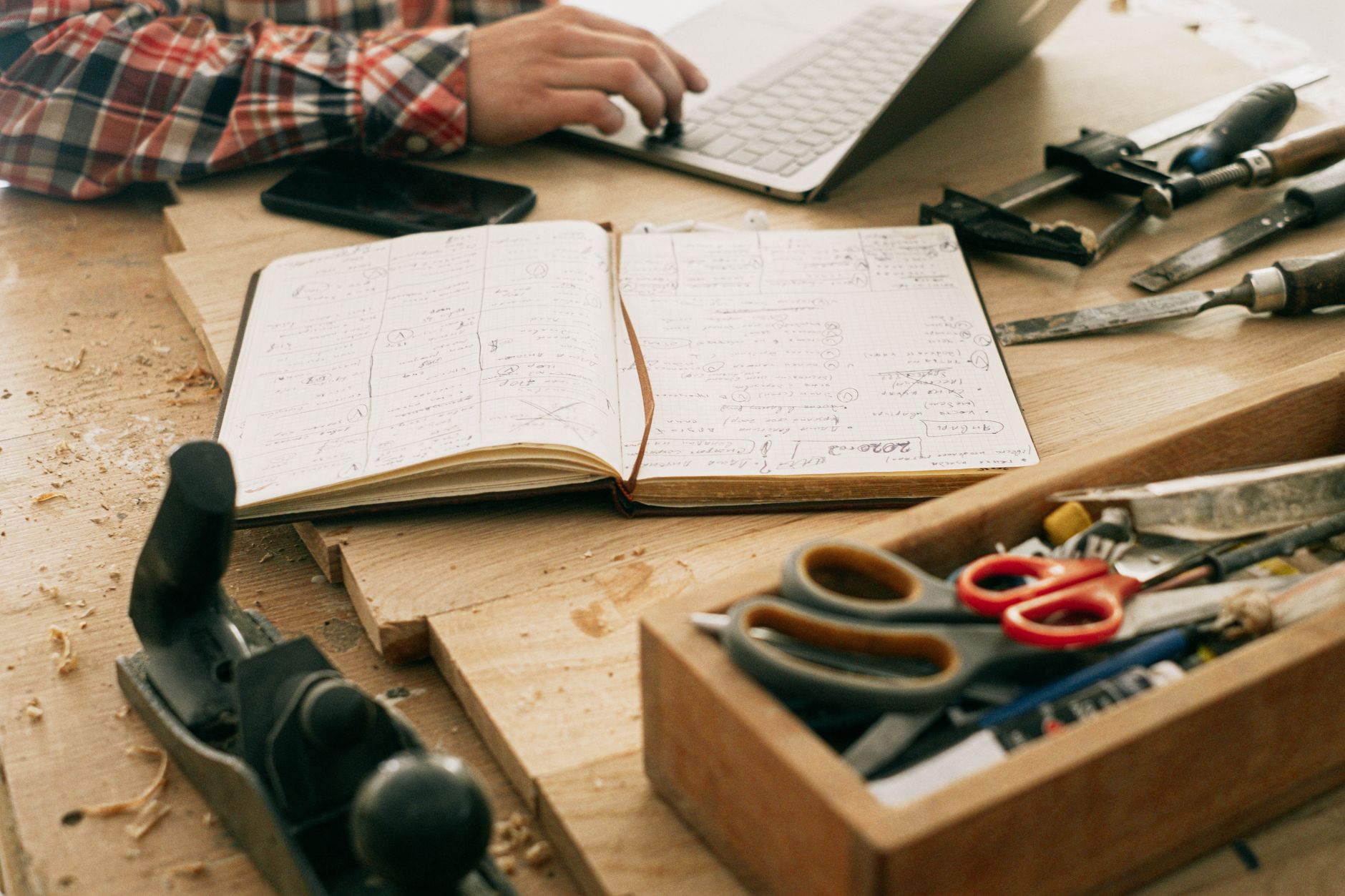 A tidy home desk set up with a laptop, notebook and tools, ready for planning a website project
